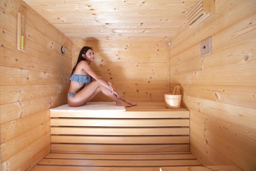 Una donna è seduta in una sauna di QC House - Chalet con Sauna a Santa Caterina Valfurva