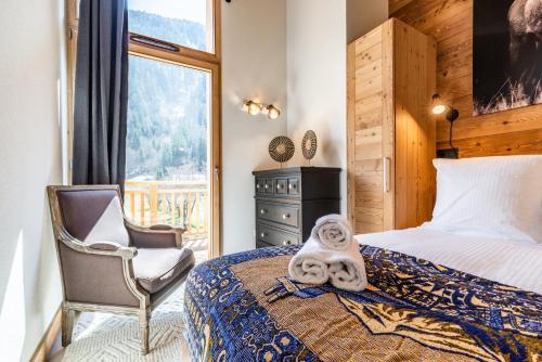 1 dormitorio con 1 cama, 1 silla y 1 ventana en Sapelli apartment Argentière Chamonix - by EMERALD STAY en Chamonix-Mont-Blanc