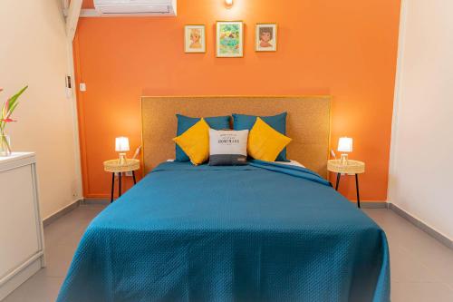 a bedroom with a blue bed with an orange wall at Villa Arc-en-ciel in Le Moule