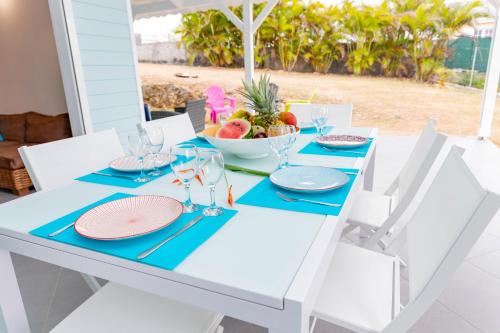 een witte tafel met blauwe servetten en een fruitschaal bij Villa Arc-en-ciel in Le Moule