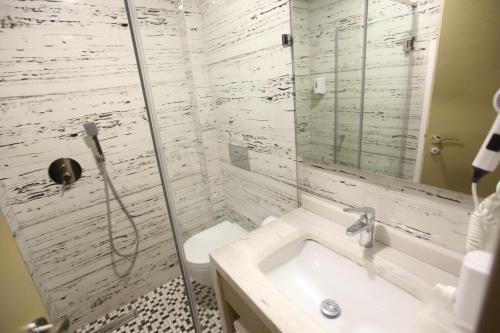 a white bathroom with a shower and a sink at Hotel Alpin Llogara in Llogara
