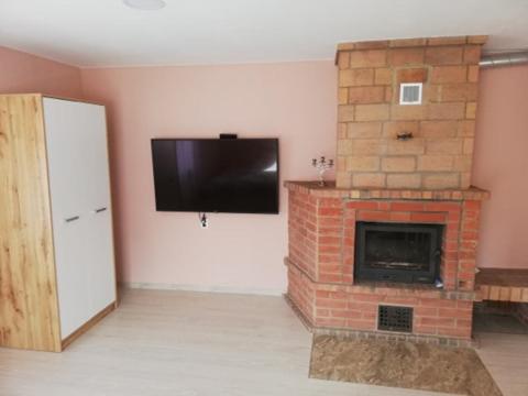 a room with a brick fireplace with a flat screen tv at VĖJO16 in Biržai