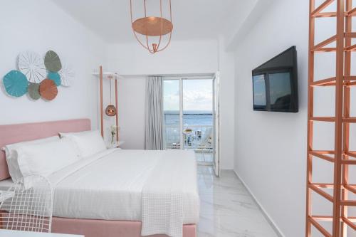 a white bedroom with a bed and a television at Nama Boutique Hotel in Tinos Town