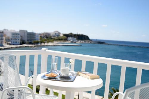 a table with a cup of coffee and a book on a balcony at Nama Boutique Hotel in Tinos Town