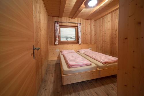 a small room with a bed in a wooden cabin at Almhütte Tirler Schweige in Alpe di Siusi
