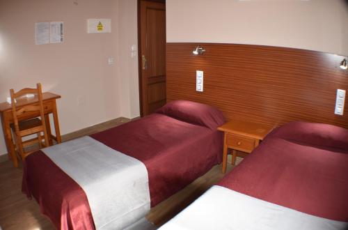 a hotel room with two beds and a desk at Hostal Alamare in Seville