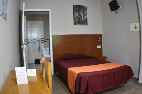 a room with a bed and a table and a bathroom at Hostal Alamare in Seville