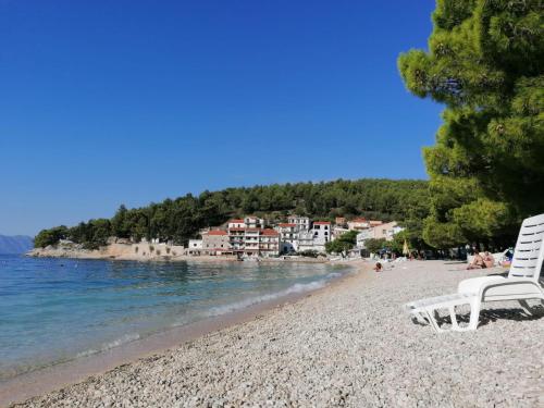 a white chair sitting on a beach next to the water at Apartments with sea view Drvenik Makarska riviera in Drvenik