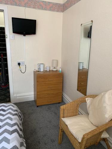 una habitación con un televisor, una silla y un espejo en Alondra Hotel, en Blackpool