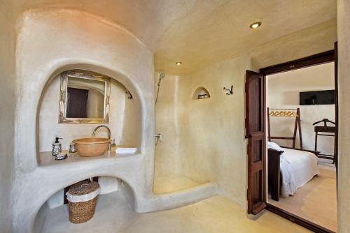 uma casa de banho com um lavatório, um chuveiro e uma cama. em Azalea Houses em Oia