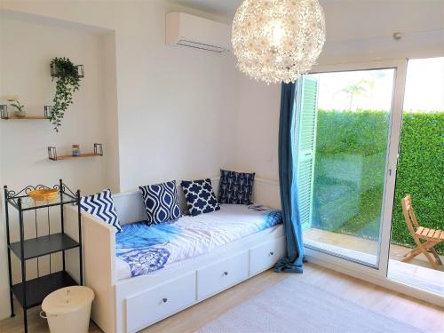 une pièce avec un canapé et une fenêtre avec un lustre dans l'établissement Promenade proche mer 01, à Nice