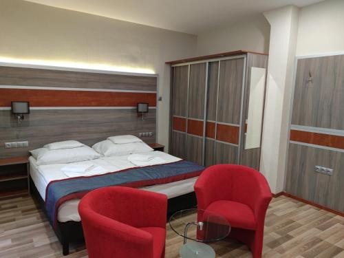 1 dormitorio con 1 cama y 2 sillas rojas en Fortuna Hotel, en Miskolctapolca