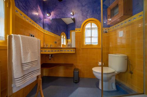 a bathroom with a toilet and yellow tiled walls at Castillo Can Xirau Piscina Privada Vistas Mar Aire Acondicionado in Santa Susanna