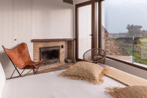 a bedroom with a fireplace and a chair and a bed at Quinta do Freixo in Benafim
