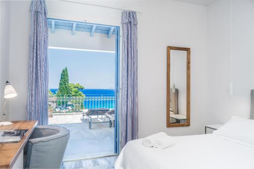 a bedroom with a bed and a desk and a window at Armonia Bay Hotel in Kokkari