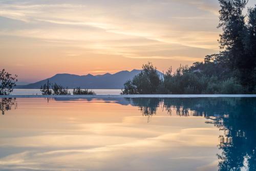 a lake at sunset with mountains in the background at Armonia Bay Hotel in Kokkari