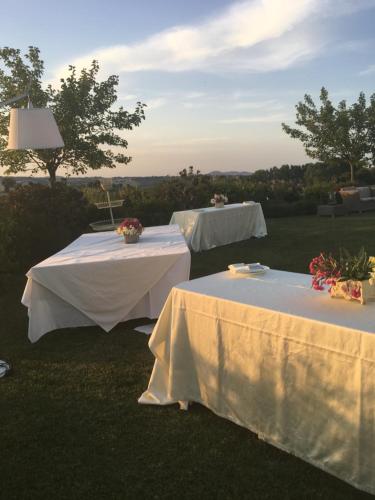 two white tables with flowers on top of the grass at Relais Il Margarito in Montefano