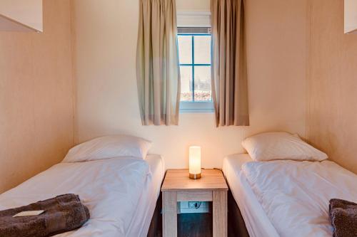 two twin beds in a room with a window at Chalet park Kroondomein Giethoorn in Giethoorn