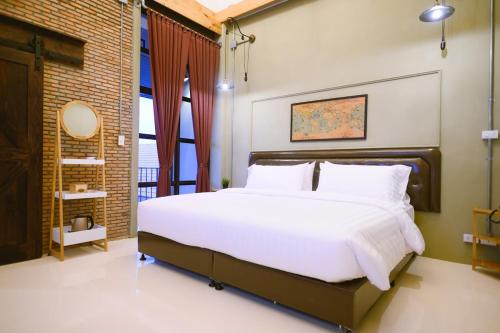 a bedroom with a large white bed and a window at Dream Factory Hotel in Udon Thani