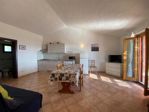 a living room with a table and a kitchen at Appartamenti Cala d'Ambra in San Teodoro