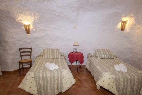 2 Betten in einem Zimmer mit einem Tisch und einem Stuhl in der Unterkunft Casas Cueva el Mirador de Galera in Galera