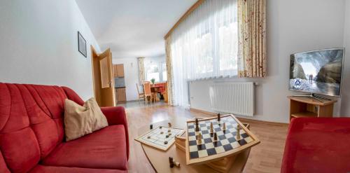 sala de estar con sofá rojo y tablero de ajedrez sobre una mesa en Adlerhof, en Sankt Leonhard im Pitztal