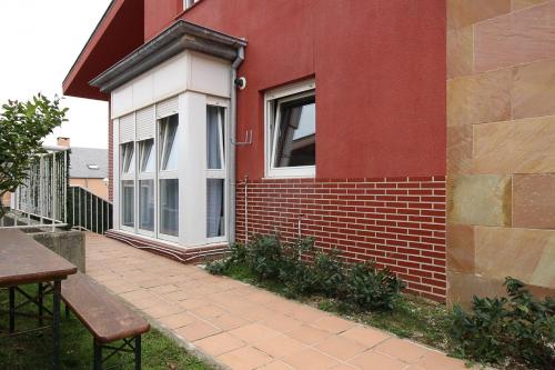 a red brick house with a window and a table at Apartamentos El Cuco in Boó de Piélagos