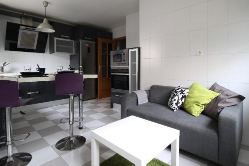 a living room with a couch and a kitchen at Apartamentos El Cuco in Boó de Piélagos