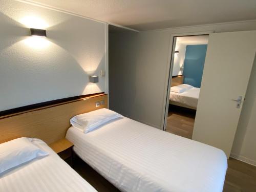 a hotel room with two beds and a mirror at Kyriad Direct Roanne Hôtel in Roanne