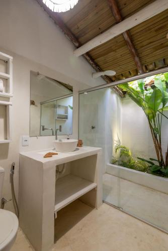 a bathroom with a sink and a shower and a mirror at Casa da Glória Trancoso - Pousada Boutique in Trancoso