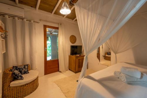 a bedroom with a bed and a chair and a television at Casa da Glória Trancoso - Pousada Boutique in Trancoso