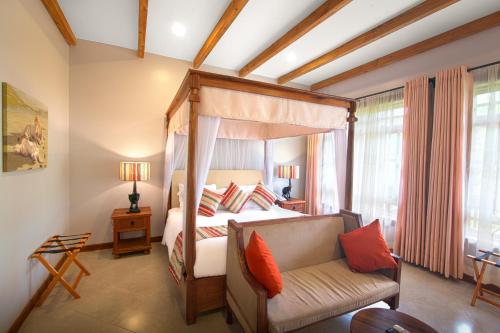 a bedroom with a canopy bed and a couch at Airport Planet Lodge in Kingori