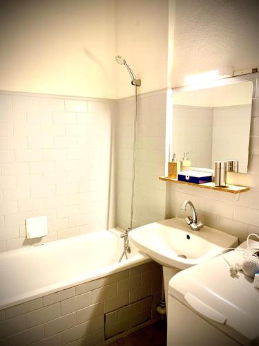 une salle de bain avec un lavabo, une baignoire et un miroir dans l'établissement Just Like home in Carcassonne, à Carcassonne