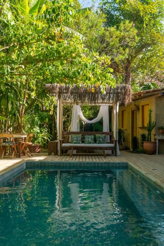 a pergola with a bench next to a swimming pool at Casa da Glória Trancoso - Pousada Boutique in Trancoso