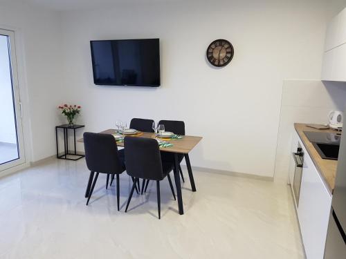 a dining room table with chairs and a clock on a wall at La Vista apartments in Mimice