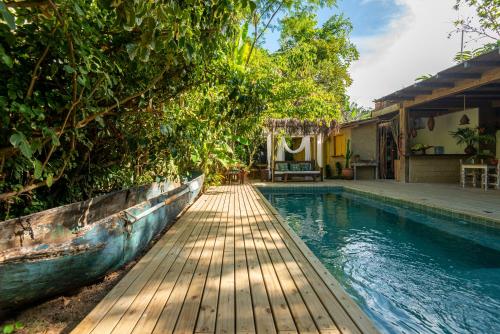 a swimming pool with a wooden walkway next to a house at Casa da Glória Trancoso - Pousada Boutique in Trancoso