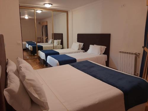 ジェレスにあるModerna do Geres Hotelのベッド3台と鏡が備わるホテルルーム