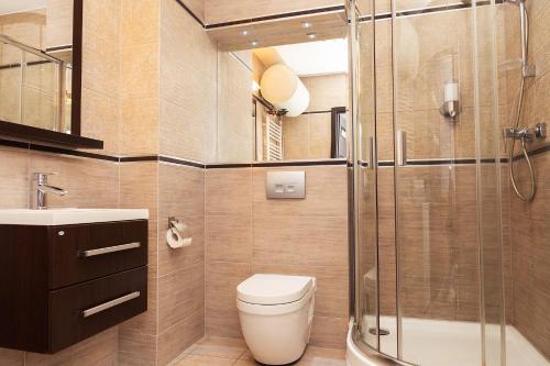 a bathroom with a shower and a toilet and a sink at Apartament Maxim in Darłówko