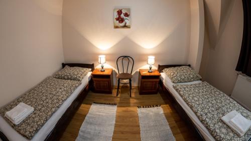 two beds in a room with a chair and two desks at Megálló Wellness Panzió in Pálháza