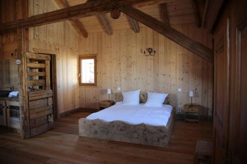 a bedroom with a large bed in a wooden room at La Grande Marguerite in Les Fourgs