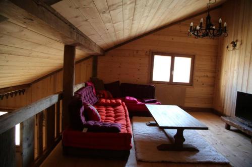 a living room with a red couch and a table at La Grande Marguerite in Les Fourgs
