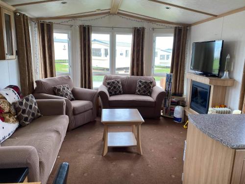 a living room with couches and a tv and a table at ChapmanHolidayLets Cayton Bay in Cayton