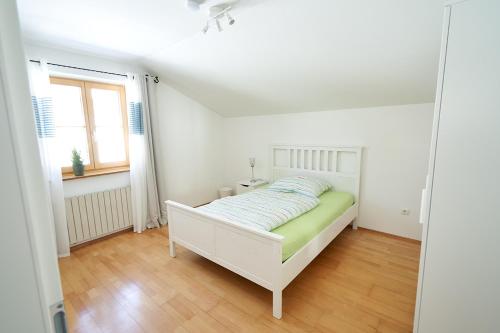 a white bedroom with a bed and a window at Bergblick Acht Mondsee in Innerschwand am Mondsee