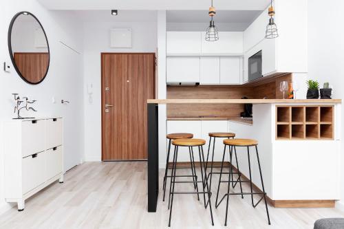 a kitchen with white cabinets and bar stools at Apartament Maxim Premium in Darłowo