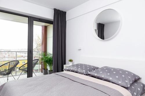 a bedroom with a bed with a mirror and a balcony at Apartament Maxim Premium in Darłowo