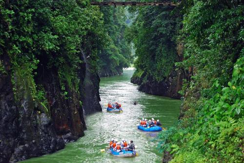 a group of people rafting down a river in canoes at Pacuare Lodge by Böëna in Bajo Tigre