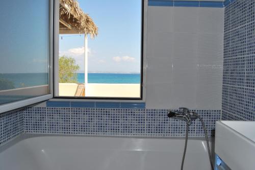 a bathroom with a tub with a view of the ocean at Spiti Anatoli in Karfas