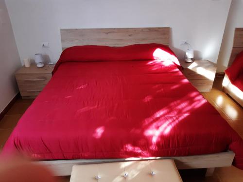 a red bed with a red blanket on top of it at Small Flat in Scafa