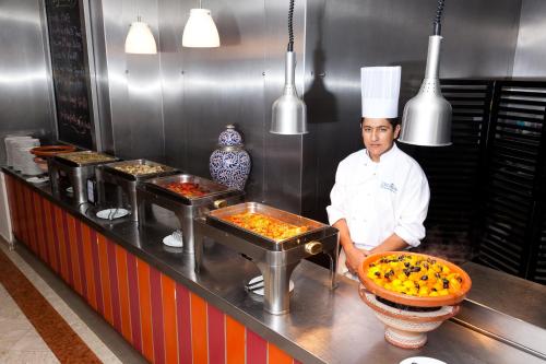 a chef standing in a kitchen with some food at Royal Decameron Tafoukt Beach Resort & Spa - All Inclusive in Agadir