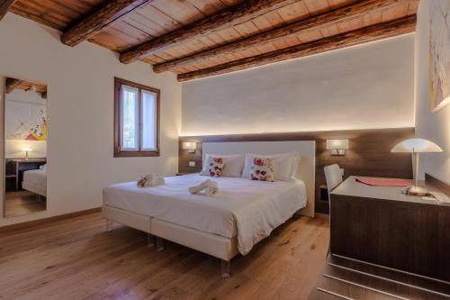 a bedroom with a large white bed and a desk at Ciasa De Gahja in Budòio
